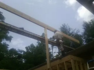 Carpenter setting a ridge beam over a new addition frame — Ice Dam Removal by Roofing Brothers in Bond