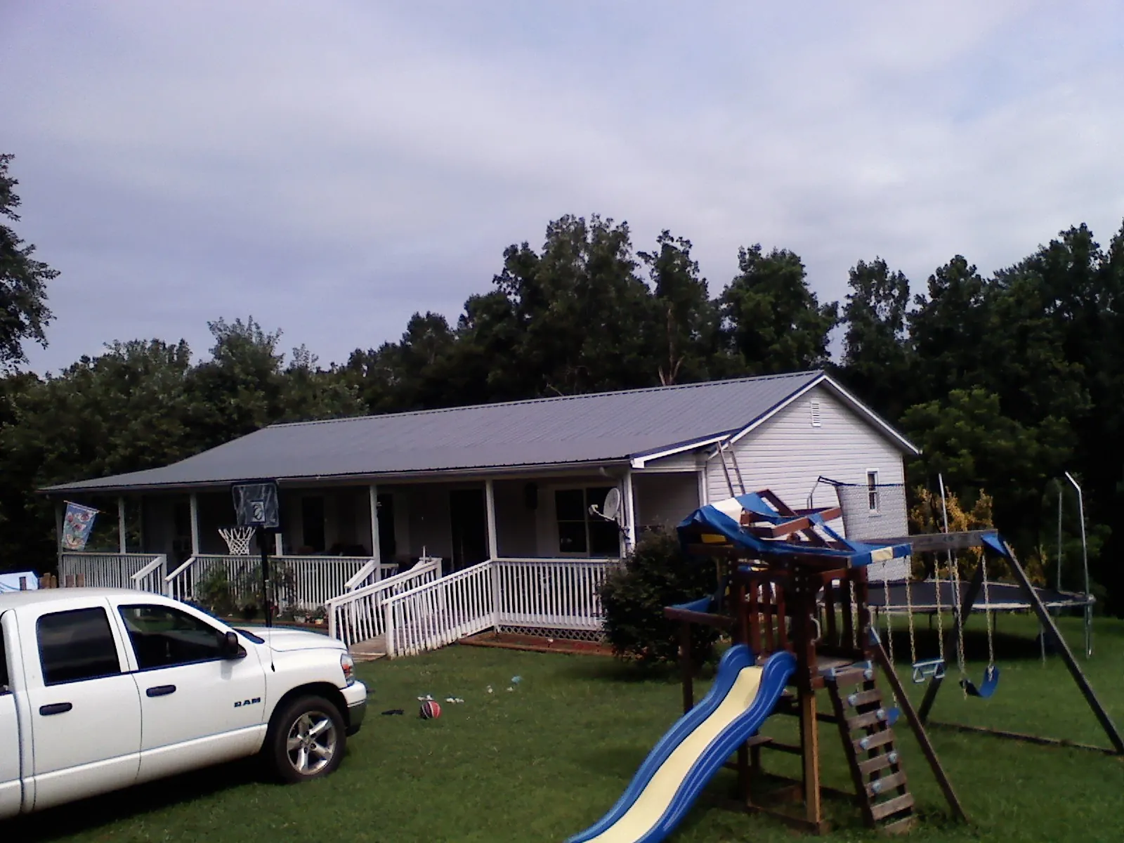Dark metal roof on a country home with a full length front porch in Bond