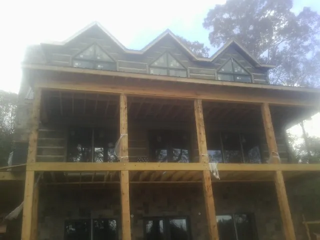 Dormers and porch framing on a large log home under construction — Roof Coating work by our crew in Bond
