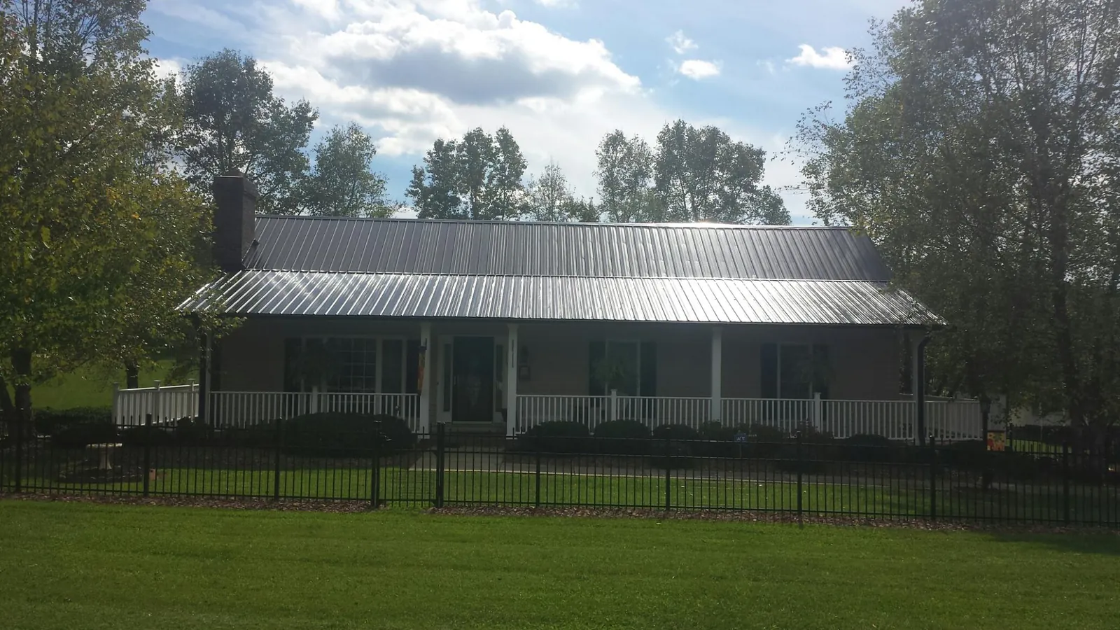 Gray metal roof on a brick ranch with a full width front porch — Gutter Guard Installation work by our crew in Bond
